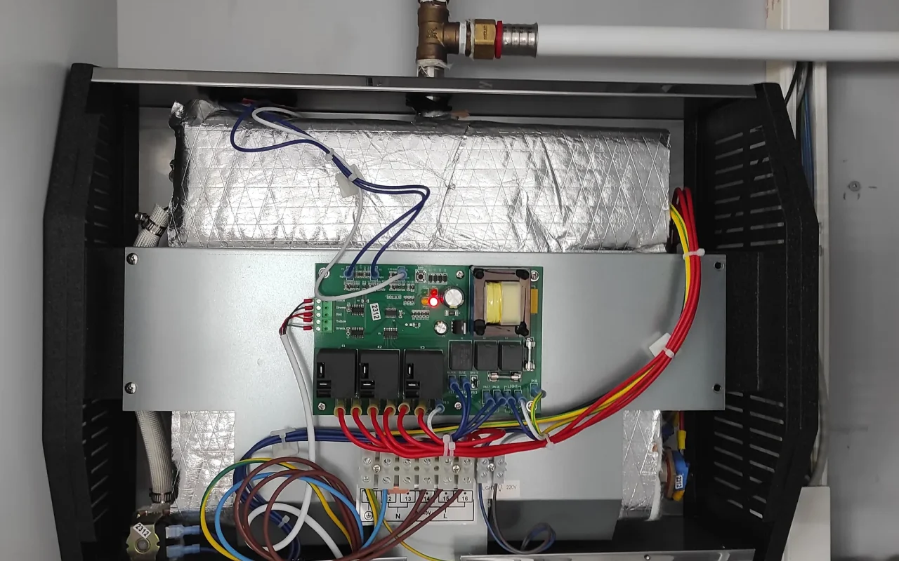 Generador de vapor abierto, con la placa electrónica, el cableado y las conexiones de agua a la vista