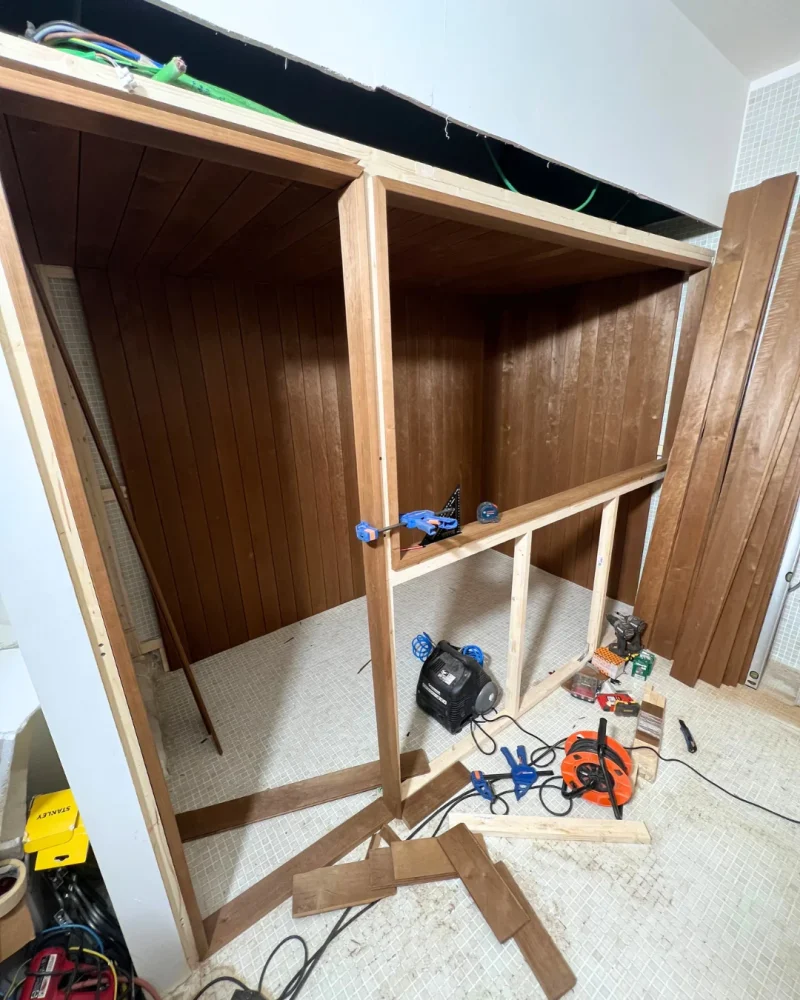 El revestimiento interior de madera cerrado sobre el bastidor, con los recortes y la fresadora todavía por el suelo del baño.