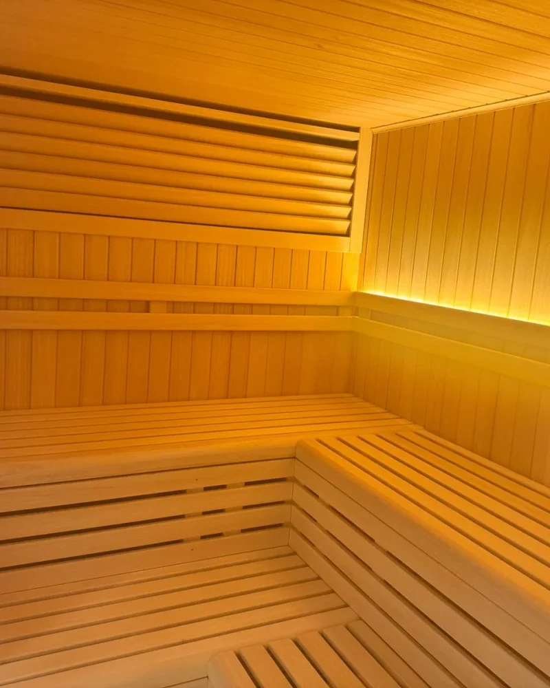 Sauna de interior con los bancos dispuestos en L y una luz indirecta que recorre todo el respaldo.