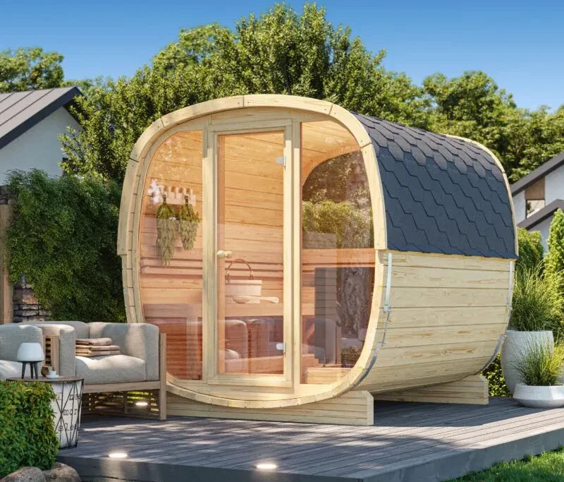 Sauna de exterior prefabricada de formas redondeadas, en abeto nórdico y con el frente de cristal, sobre una tarima en un jardín
