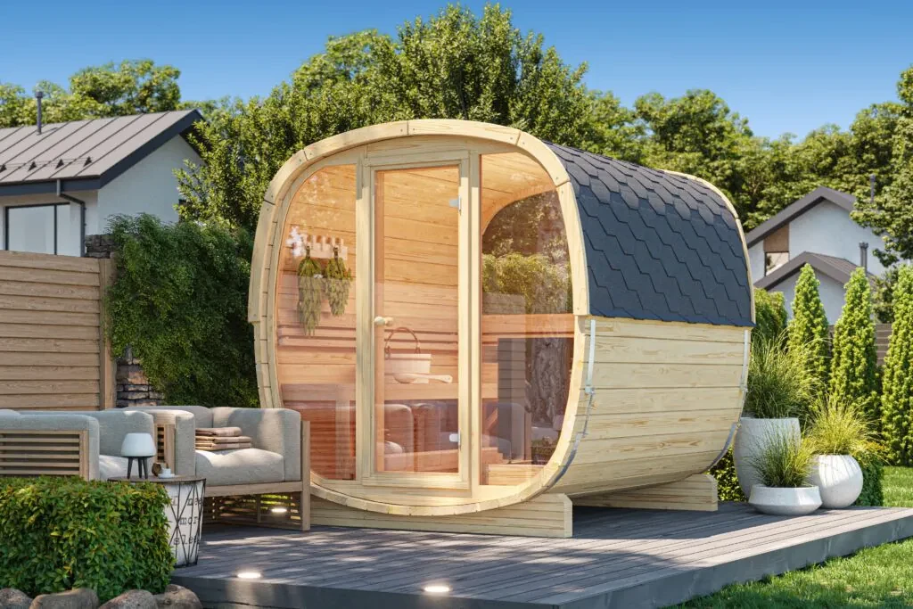 Sauna de exterior prefabricada de formas redondeadas, en abeto nórdico y con el frente de cristal, sobre una tarima en un jardín